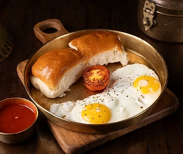 Fried eggs with pav on a brass pan