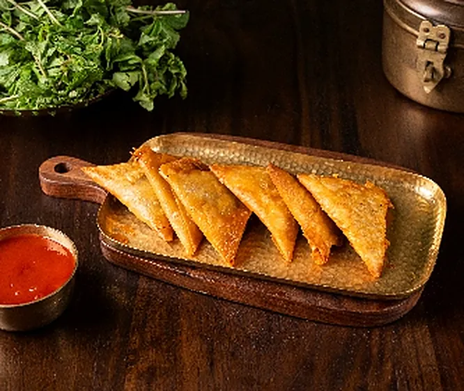 Golden samosas on a brass tray
